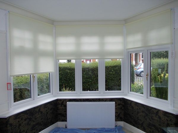 roller blinds in a three sided bay window with the blinds part lowered