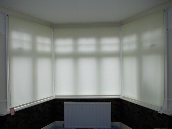 roller blinds in a three sided bay window with the blinds lowered all the way