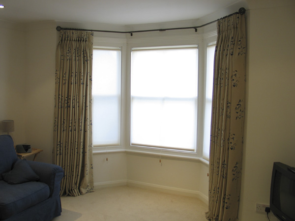Sanderson printed linen, pinch pleats on a bay pole with roller blinds in this lower ground floor window