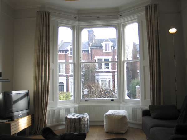 Linen curtains on a 25mm polished steel bay window pole from The Bradley Collection