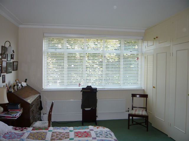 Three white 50mm slatted wood blinds - part closed