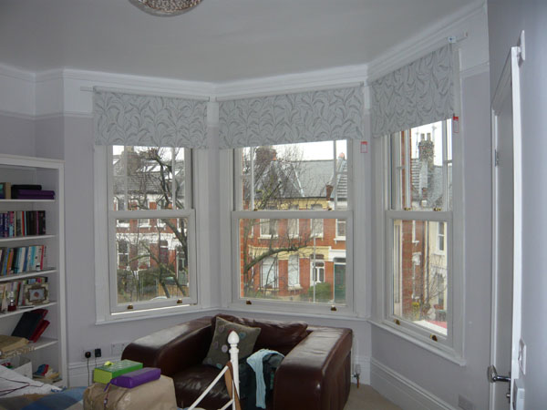 Blackout roller blinds lowered part way in this bay window