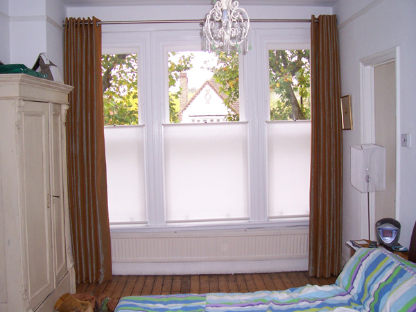 Artificial silk curtains eyeletted on a pole with bottom up blinds for privacy