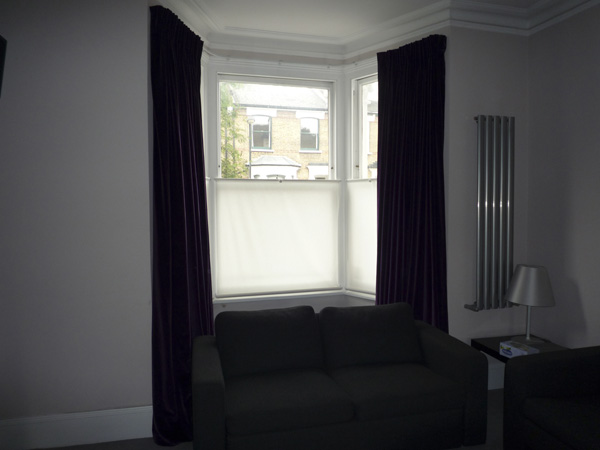 Velvet curtains, interlined and pinch-pleated, on corded steel bay window track together with simple bottom up blinds for privacy