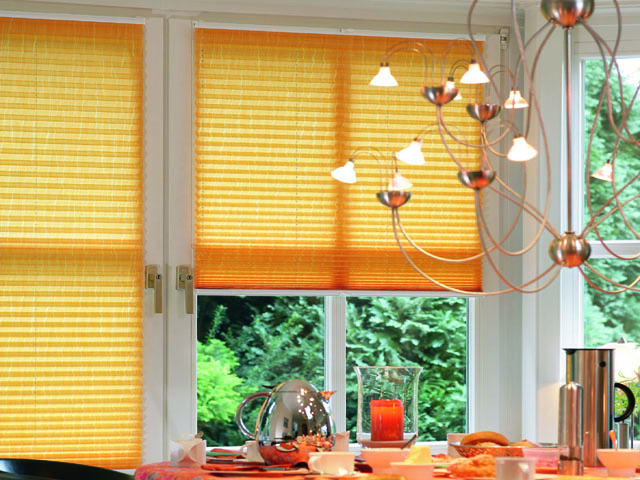 Yellow pleated blinds fitted to opening windows, attached top and bottom so that the windows operate normally 