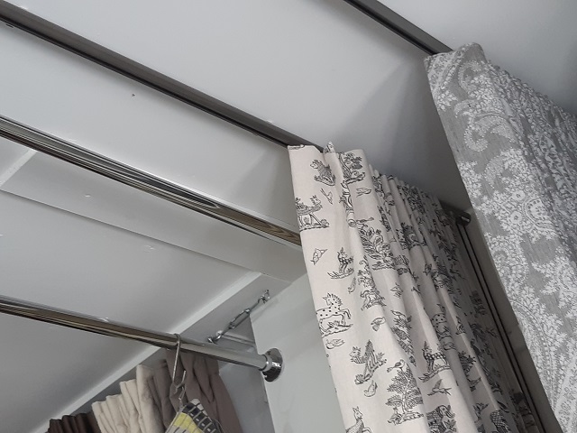 Cartridge Pleat curtain hanging below a Bradley Collection glider pole stacked back - Changing Curtains Shop Display