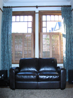 half height oiled cedar wood shutters with 47mm louvres, together with interlined, pinch pleat curtains Stroud Green